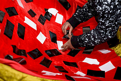 A child sticking pieces of black and white tape on red fabric