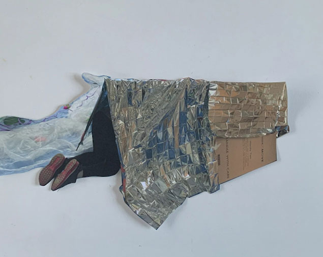 Moving image still of a participant crawling into a cardboard and foil blanket den