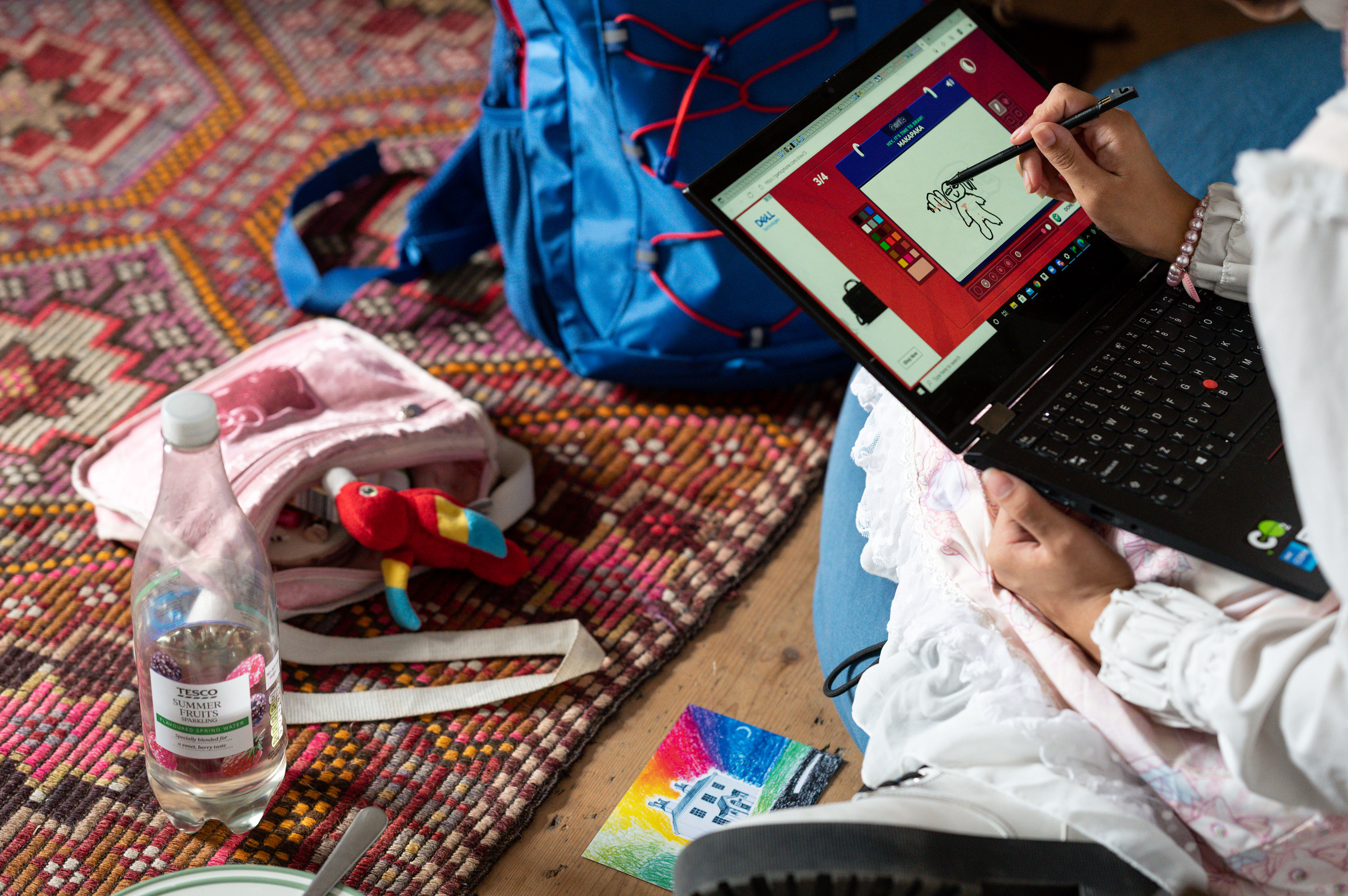 A participant sitting on the floor with a laptop and using a digital pen to create art