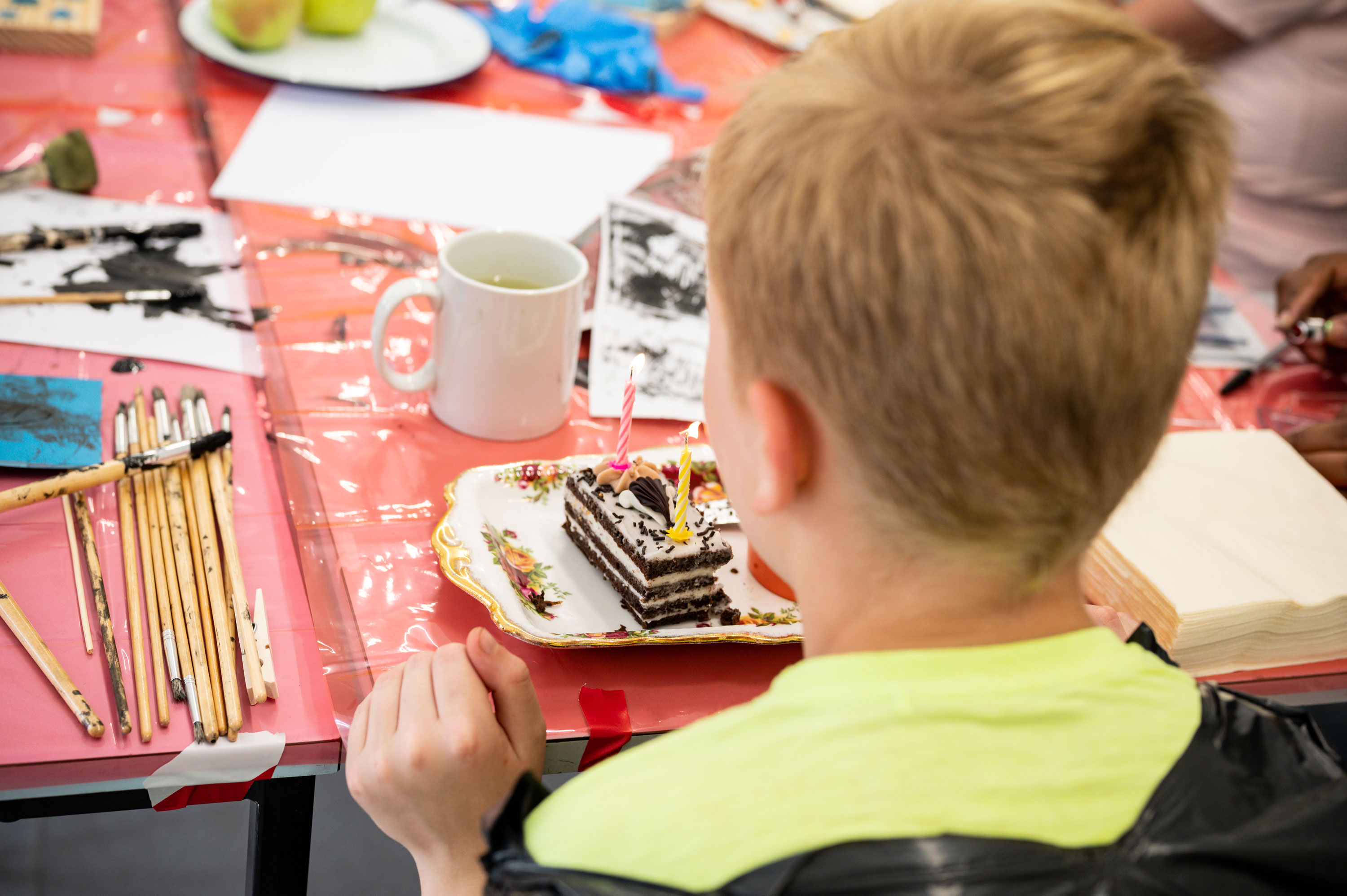 A young person sitting at a table looking at a small birthday cake