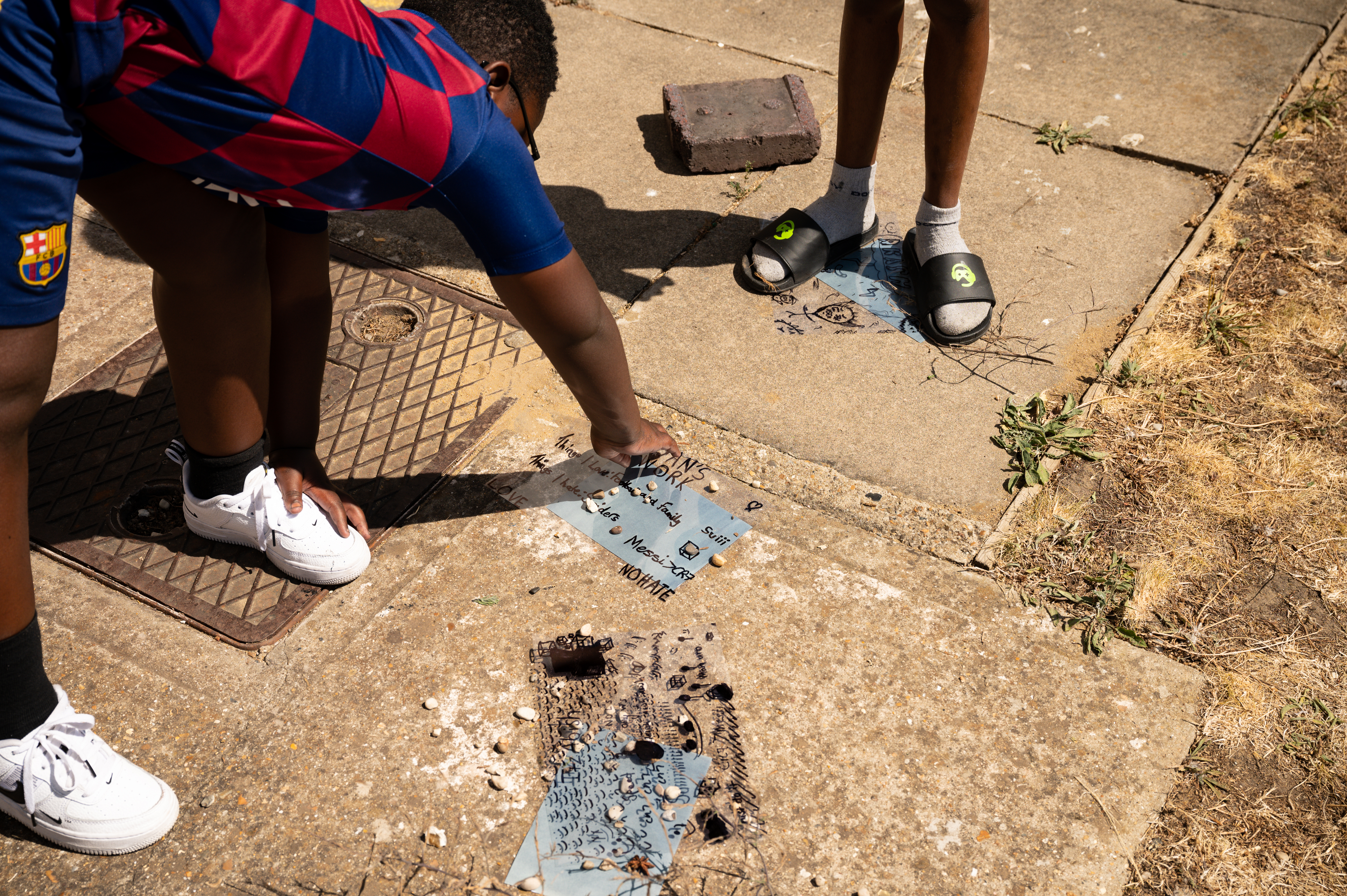 2 children stand outside making artworks in the ground