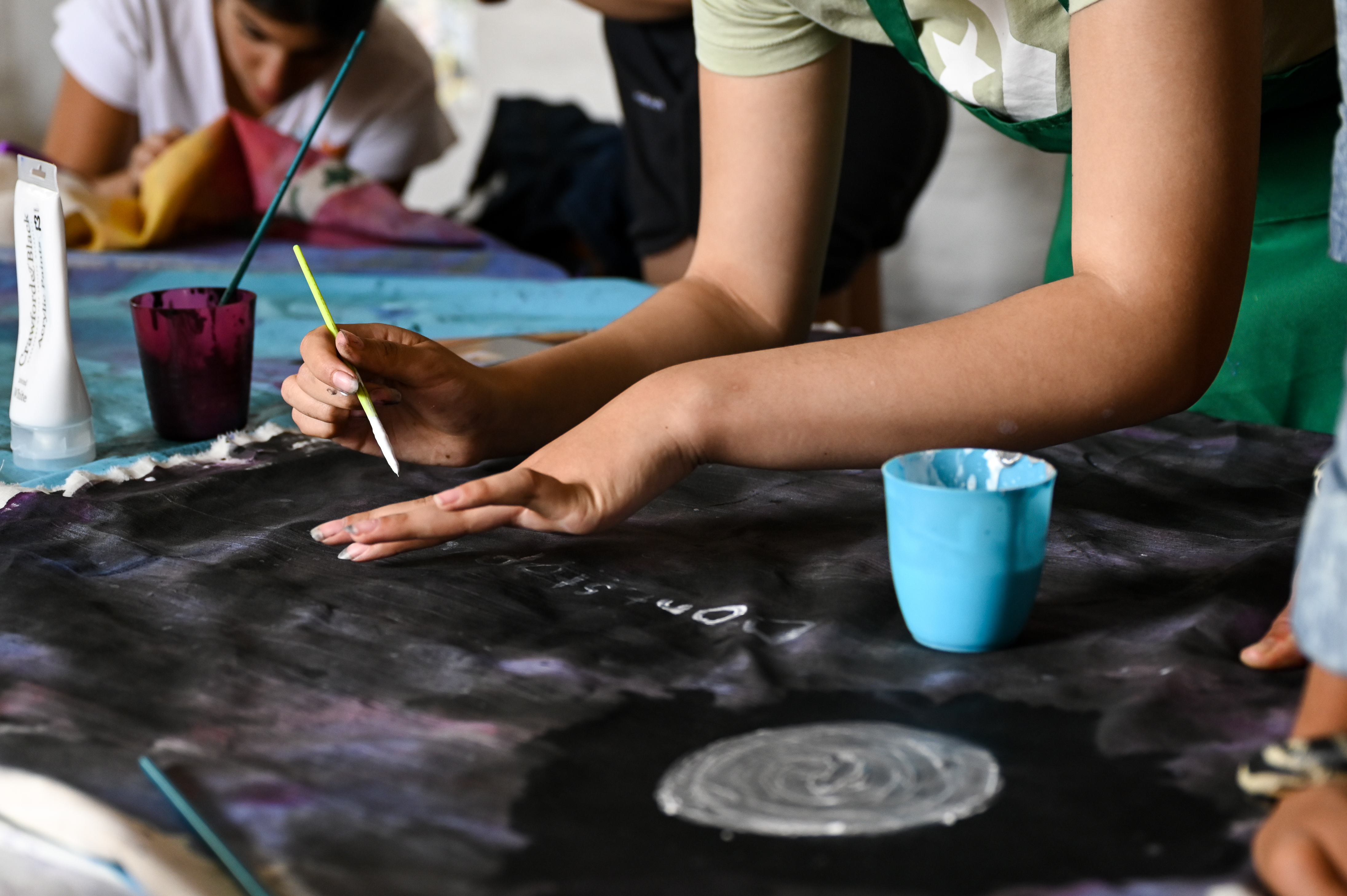 2 young people focused on writing in paint onto large banners