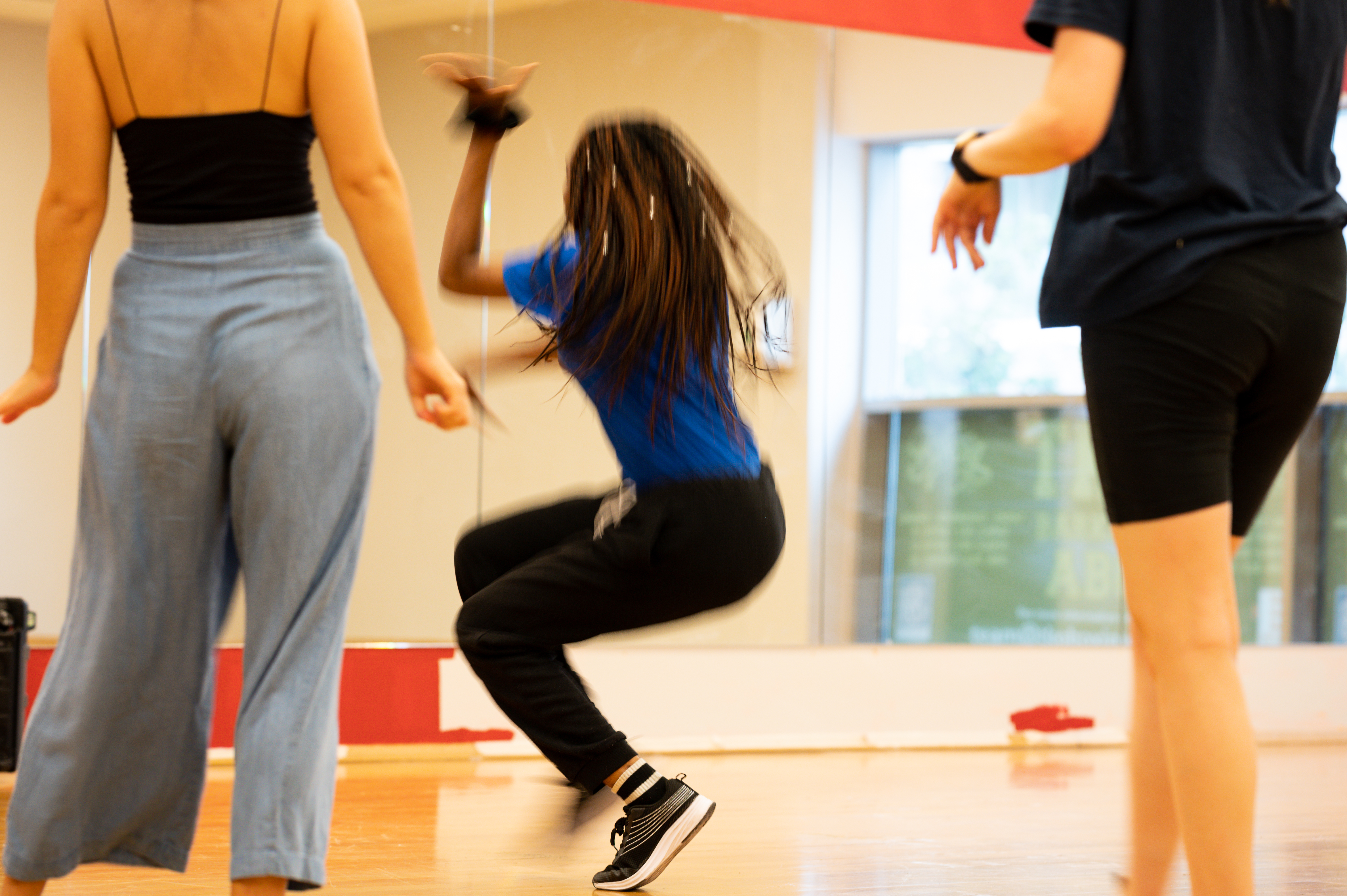 Young woman mid movement looking into dance studio mirror