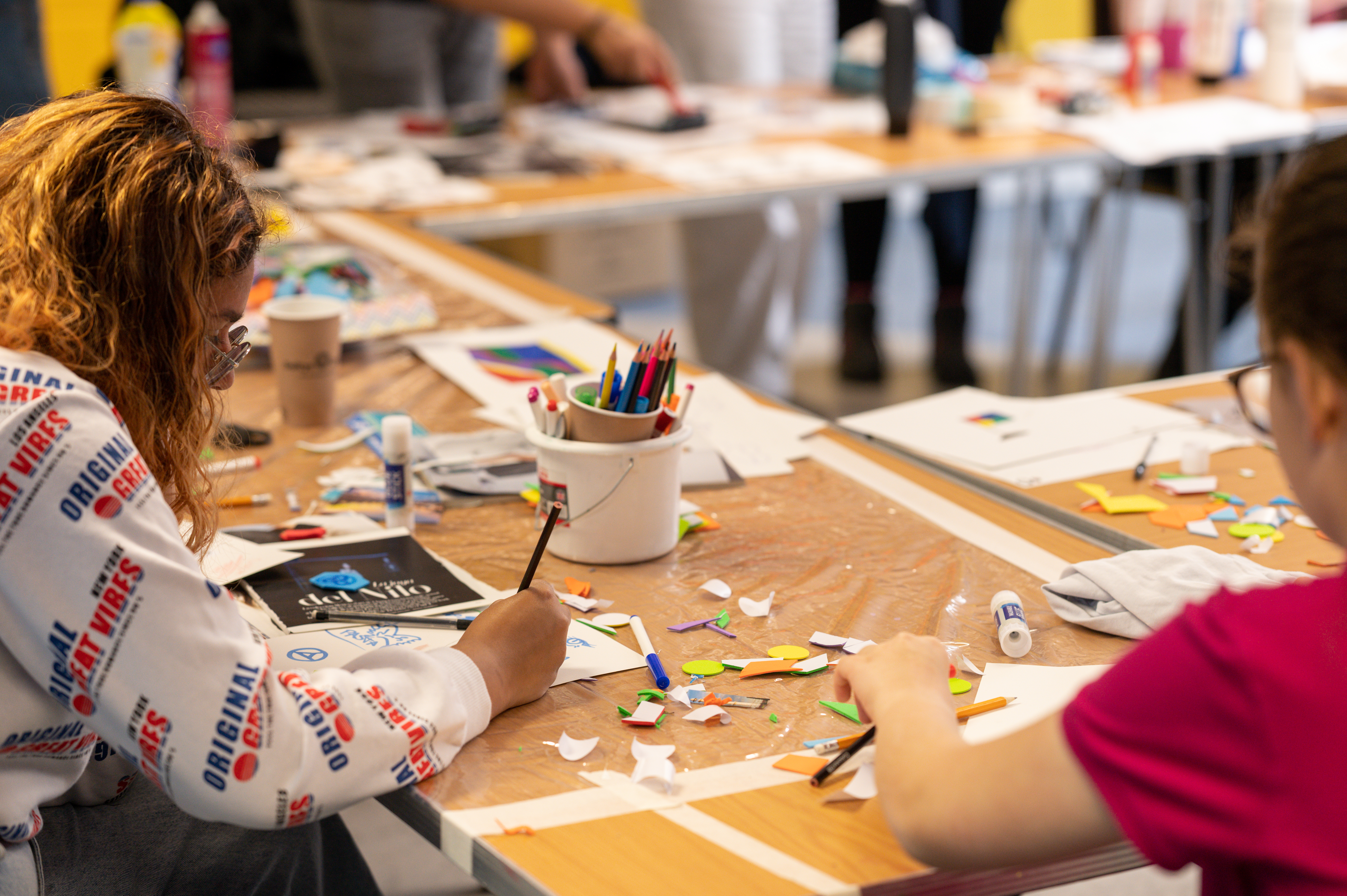 3 young people worked at a messy table with lots of art materials around them