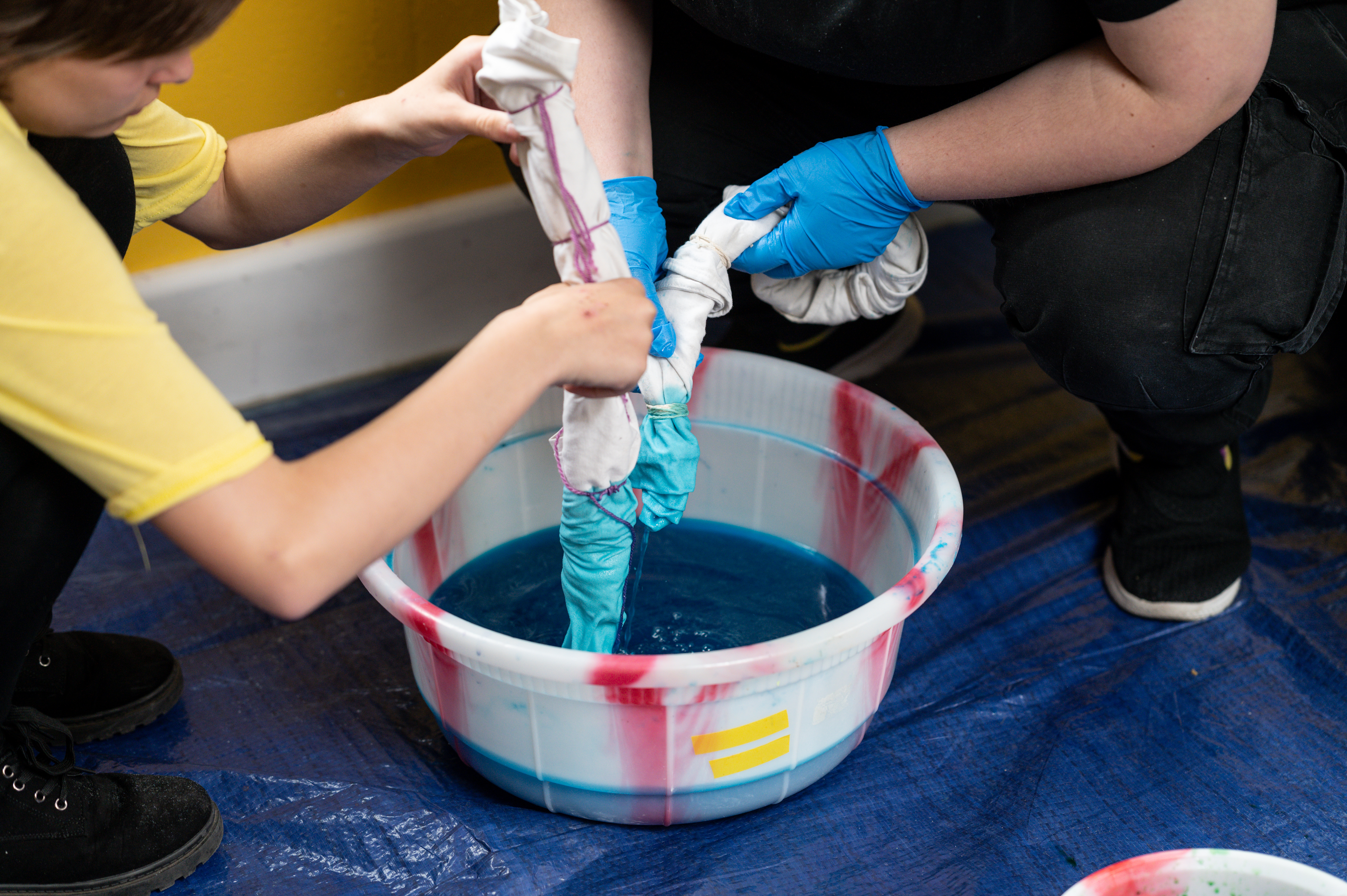 2 people squeezing dye from fabric