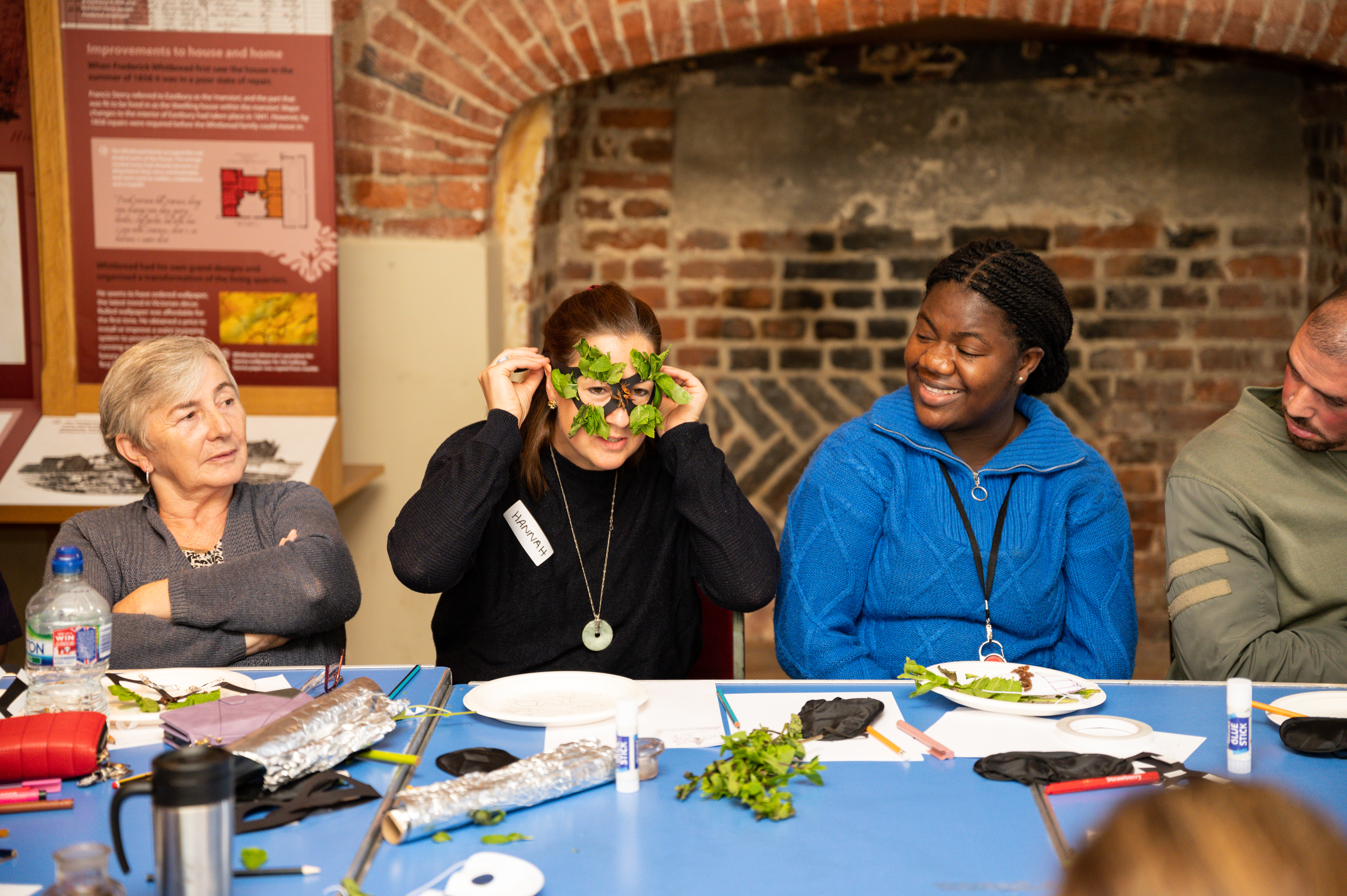 4 foster carers observing one woman demonstrating a face mask she has made.