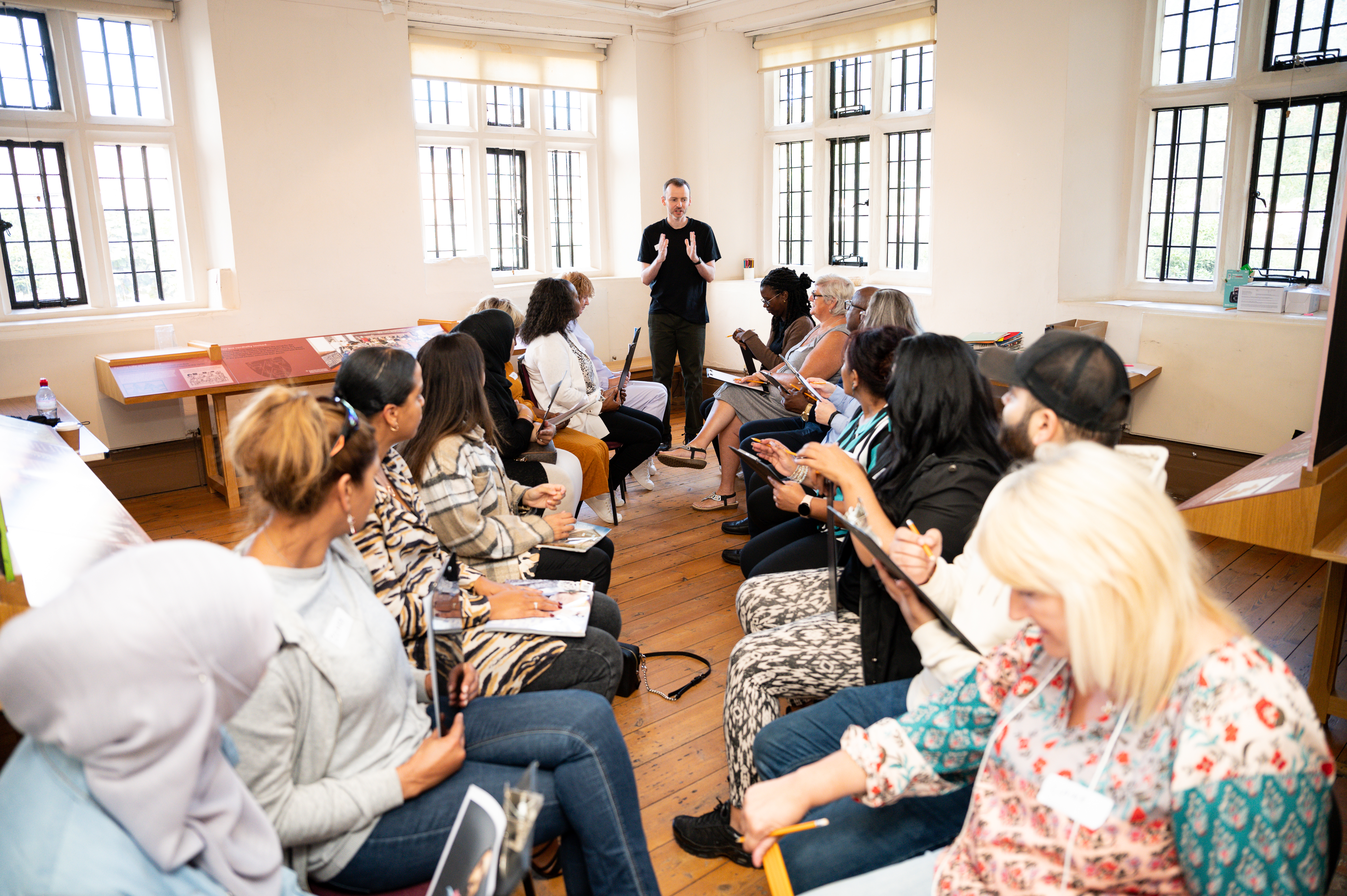 Room full of around 20 foster carer sitting in two rows facing each other